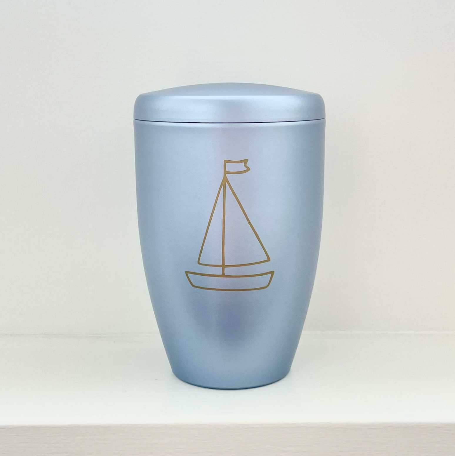 Light blue infant urn with a little tender sailing boat. Can be personalised with name and dates.