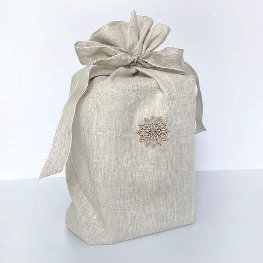 Beautiful oat-coloured linen urn for ashes with bow and a delicate wooden ornament. Completely biodegradable.
