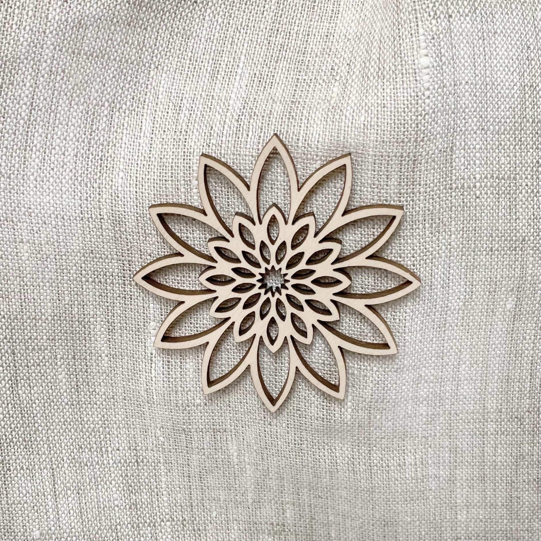 Close-up of wooden flower ornament on oatmeal coloured linen urn.