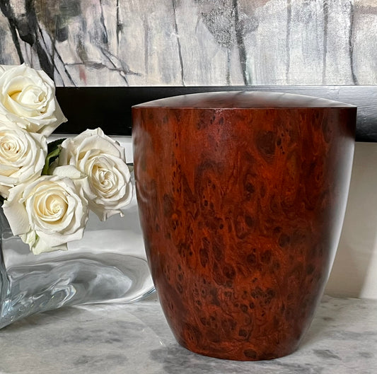 Beautiful mahogany wood imitation urn for ashes on marble console with white roses.