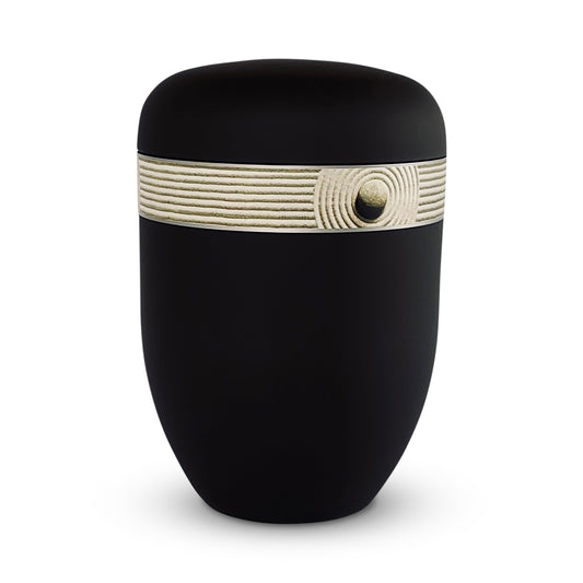 black cremation urn with elegant band of a zen pattern. in the sand