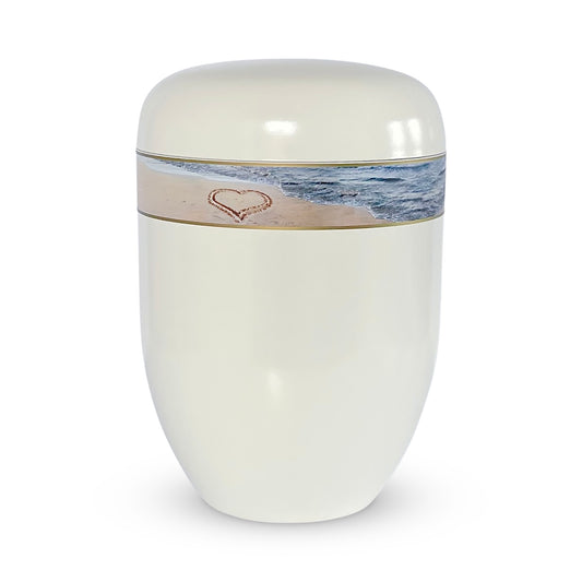 Beautiful white urn for ashes with photo band  of a heart drawn in the sand.
