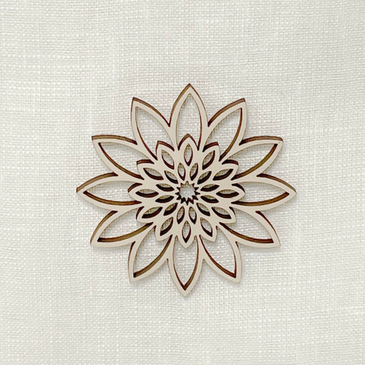 Close up of delicate wooden ornament on white linen funeral urn.
