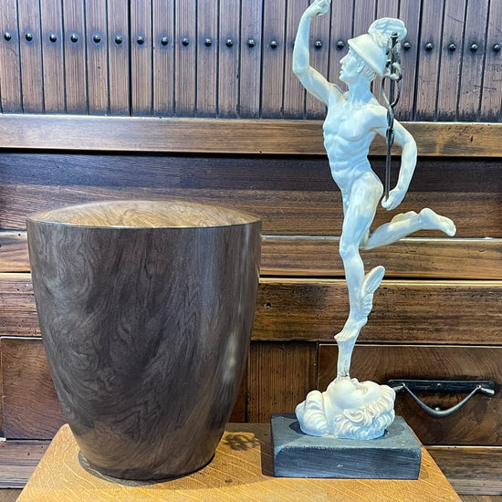 Stunning modern yet classic walnut wood imitation urn for human ashes  sitting on a wooden pedestal with a classic alabaster figurine next to it.